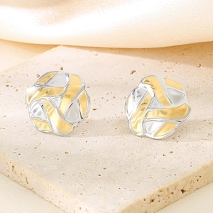 Gros plan de boucles d'oreilles nœud tressé bicolore en or et argent sur socle en pierre