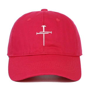 Close-up of white cross embroidery made of nails on a red cotton baseball cap