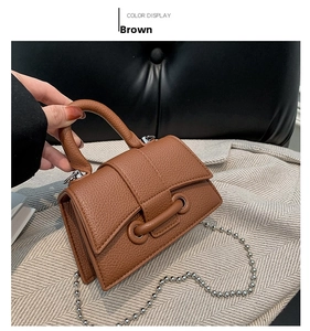 Detail of brown litchi pattern leather mini bag with silver ball chain and metal eyelets