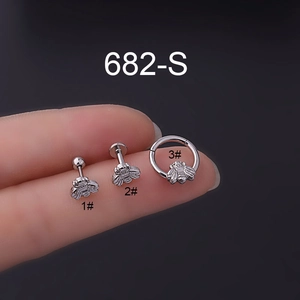 Detailed macro view of bee-shaped stainless steel piercing jewelry held on fingertips