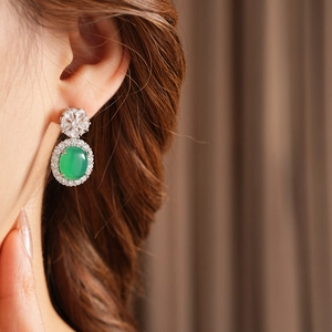 Gros plan de boucles d'oreilles vintage avec gemme verte ovale et halo de zircons