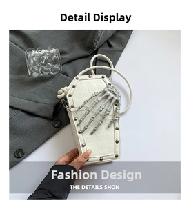 Detail of white coffin-shaped crossbody bag featuring silver skull hand and metal rivets