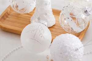 Macro detail of white glitter Christmas baubles and bells on a rustic wooden tray