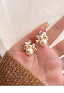 Gros plan de boucles d'oreilles perles plaquées or 18 carats avec détails de fleurs
