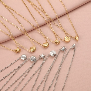 Detailed close-up of gold and silver sea star and shell necklaces on pink fabric