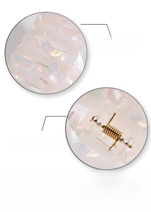 Detail of pearlescent hair claw clip showing smooth finish and strong gold metal spring