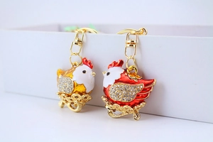 Detail of red and gold hen keychains with sparkling rhinestones and metal hollow base