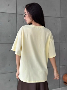 Detail of loose fit pale yellow cotton T-shirt featuring ribbed crew neck and plain back