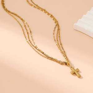 Detail einer dreilagigen Goldkette mit Kreuzanhänger und Ketten mit verschiedenen Texturen