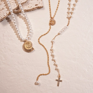Three-piece gold layered necklace set with pearls, seashell, and rhinestone cross pendant