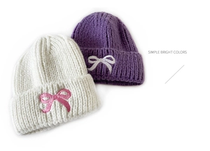 Detail of soft knit texture and delicate bow embroidery on children's winter hats