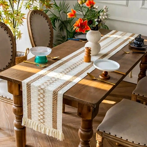 Close-up of bohemian table runner with beige and brown geometric weave and tassels