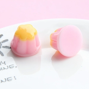 Miniature pink resin pudding charms with yellow floral tops on a white decorative plate