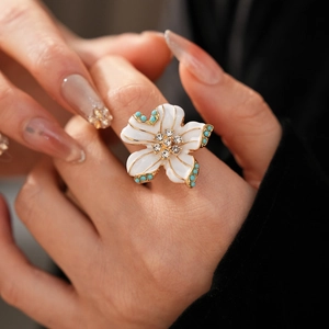 Vue macro de la bague fleur en émail blanc avec bordure dorée, strass et perles turquoise