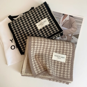 Detailed view of knitted houndstooth scarves in black and brown on a white surface
