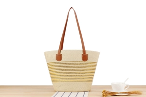 Macro shot of striped straw tote bag with brown leather handles on wooden background