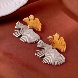 Vintage titanium steel ginkgo leaf earrings with two-tone finish on brown silk background