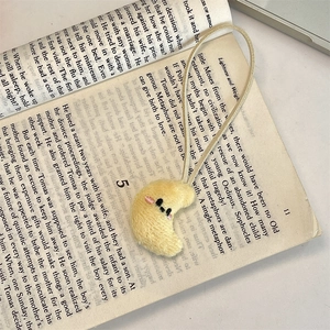 Detail shot of cute yellow plush moon pendant with embroidered face on a vintage book