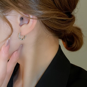 Close-up of model wearing gold and silver twisted hoop earrings with zircon stones