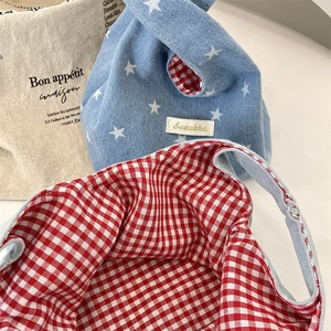 Detail of blue denim tote bag with white star pattern and red checkered inner lining
