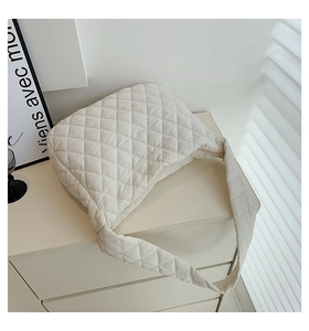Detail shot of the white quilted cloud bag's texture and matching strap on a drawer
