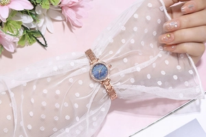 Elegant ladies rose gold watch with blue sunray dial and crystal bezel on a female wrist