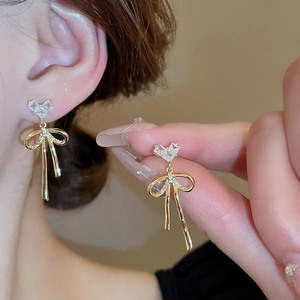 Detail view of heart-shaped zircon bow earrings showing size and gold metal texture