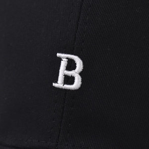 Macro detail of high-quality white 3D embroidered letter B on a black cotton baseball cap