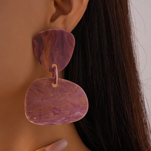 Close-up of purple resin geometric oval earrings with golden accents on a model