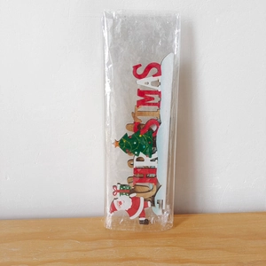 Macro shot of 3D wooden Christmas letter ornament with Santa and tree motifs in packaging