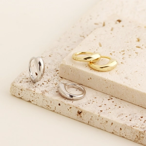 Detailed view of minimalist gold and silver S925 sterling silver hoop earrings on stone