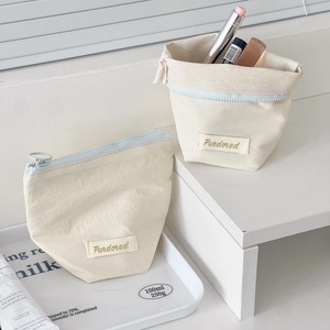 Detail view of cream canvas cosmetic pouches with zipper and Purdored brand tag