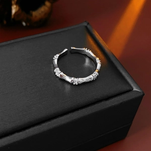 Détail macro d'une bague style bambou argentée avec zircons sur une boîte à bijoux noire
