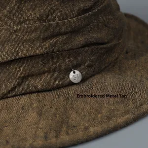 Vintage distressed linen bucket hat featuring a decorative sewn small metal label detail