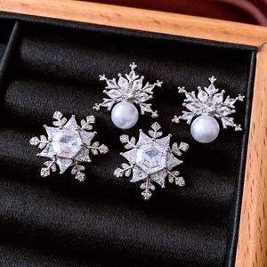 Close-up of snowflake stud earrings with pearls and cubic zirconia on black velvet