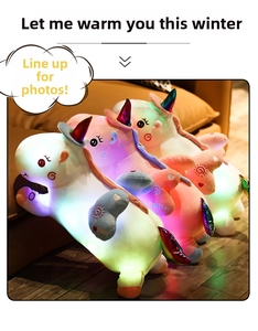 Close-up of three colorful glowing LED unicorn plush toys lined up on a cozy sofa