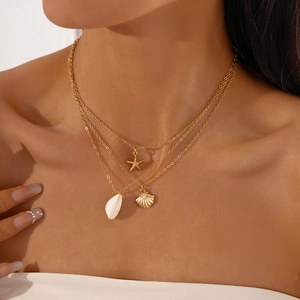Detail of three-layer gold necklace featuring starfish and seashell ocean pendants