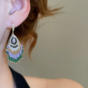 Close-up of bohemian beaded tassel earrings in purple and green worn by a model