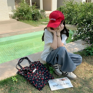 Outdoor lifestyle shot of a cherry print canvas tote bag paired with casual summer attire