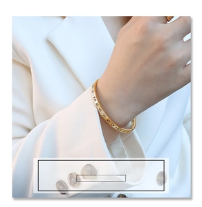 Detailed close-up of golden titanium steel bracelet with engraved Roman numerals
