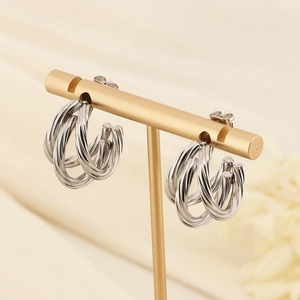 Exaggerated silver C-shaped twisted earrings displayed on a professional gold jewelry stand