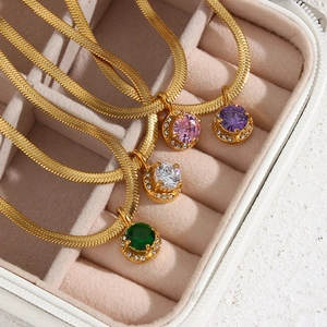 Macro detail of gold snake chains with colorful round zircon pendants in a jewelry box