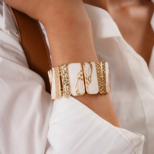 Close-up of vintage geometric elastic bracelet with gold hammering and white enamel details