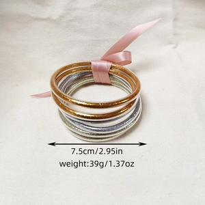 Dettaglio di bracciali glitterati da 7,5cm con nastro rosa, finiture oro e argento