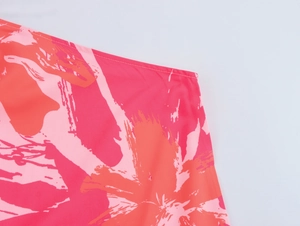Close-up of red and pink floral abstract print fabric with smooth texture and stitching
