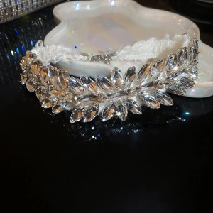 Detailed close-up of leaf-shaped crystal necklace displayed on white shell tray