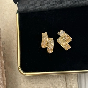 Détail macro de boucles d'oreilles en verre texturé plaqué or dans une boîte à bijoux