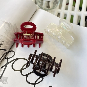Three acetate hair claws in red, pearl, and black hollow frames on a lifestyle background