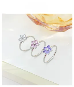 Detailed view of floral rings with purple and pink crystal petals on silver bands
