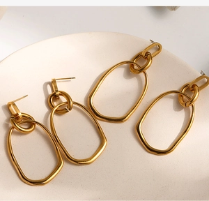 Detailed view of gold multi-layer geometric hoop earrings on a white ceramic tray